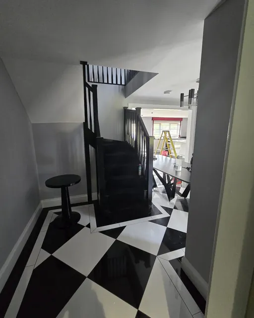 Chequerboard tiled hallway with black staircase